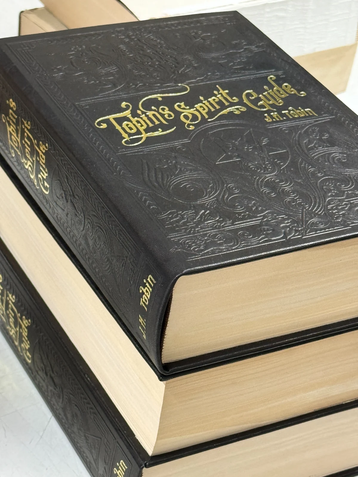Black hardback books with ornate embossed artwork and gold lettering
