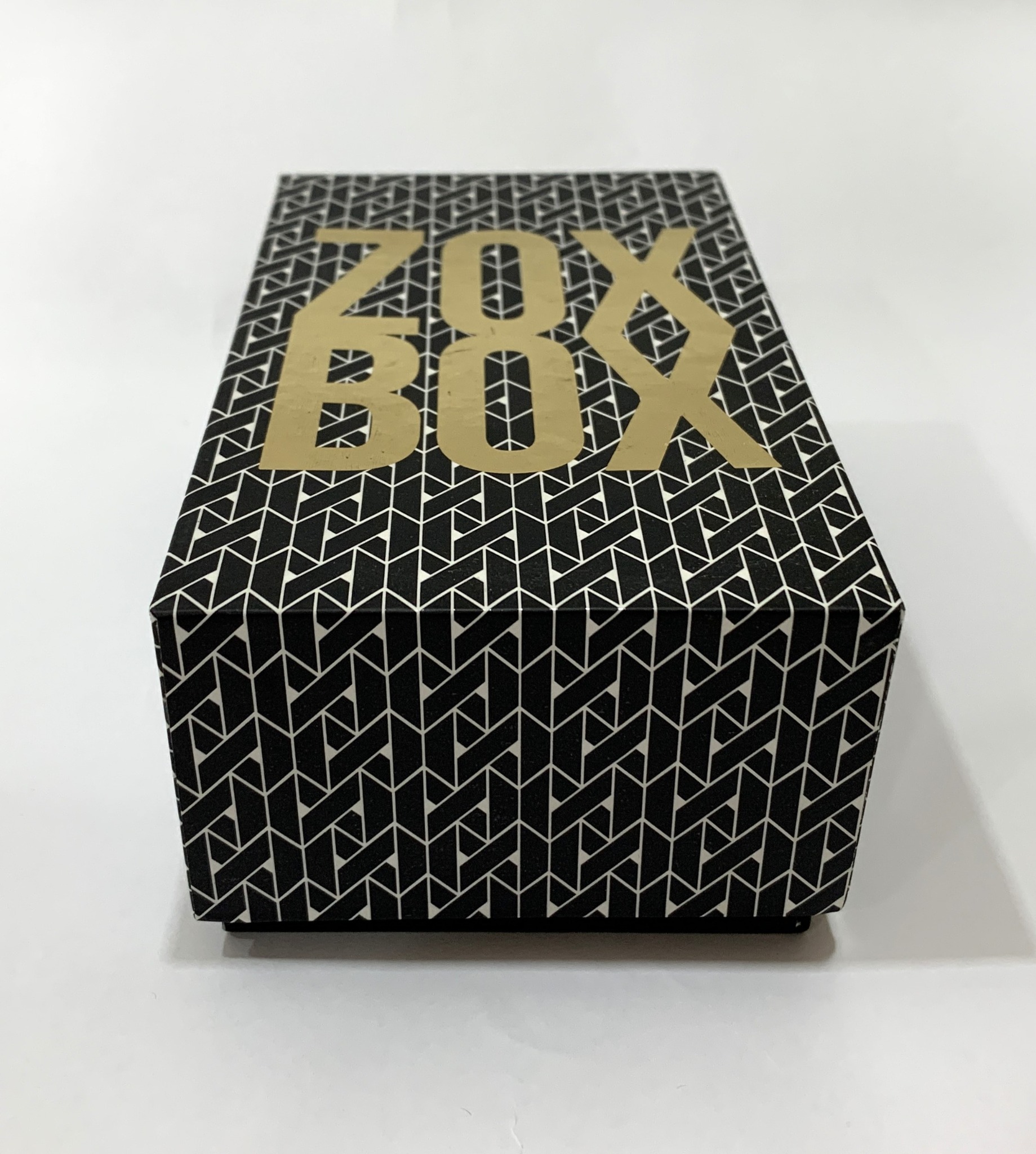 Black Zox gift box with gold lettering and a geometric pattern