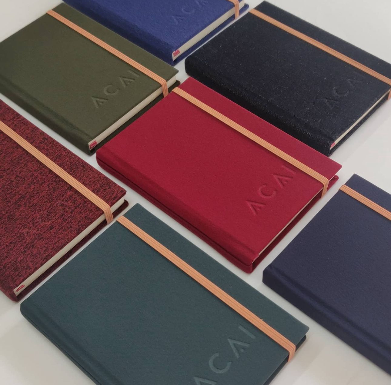 Branded red, green and blue journals with contrasting elastic closures