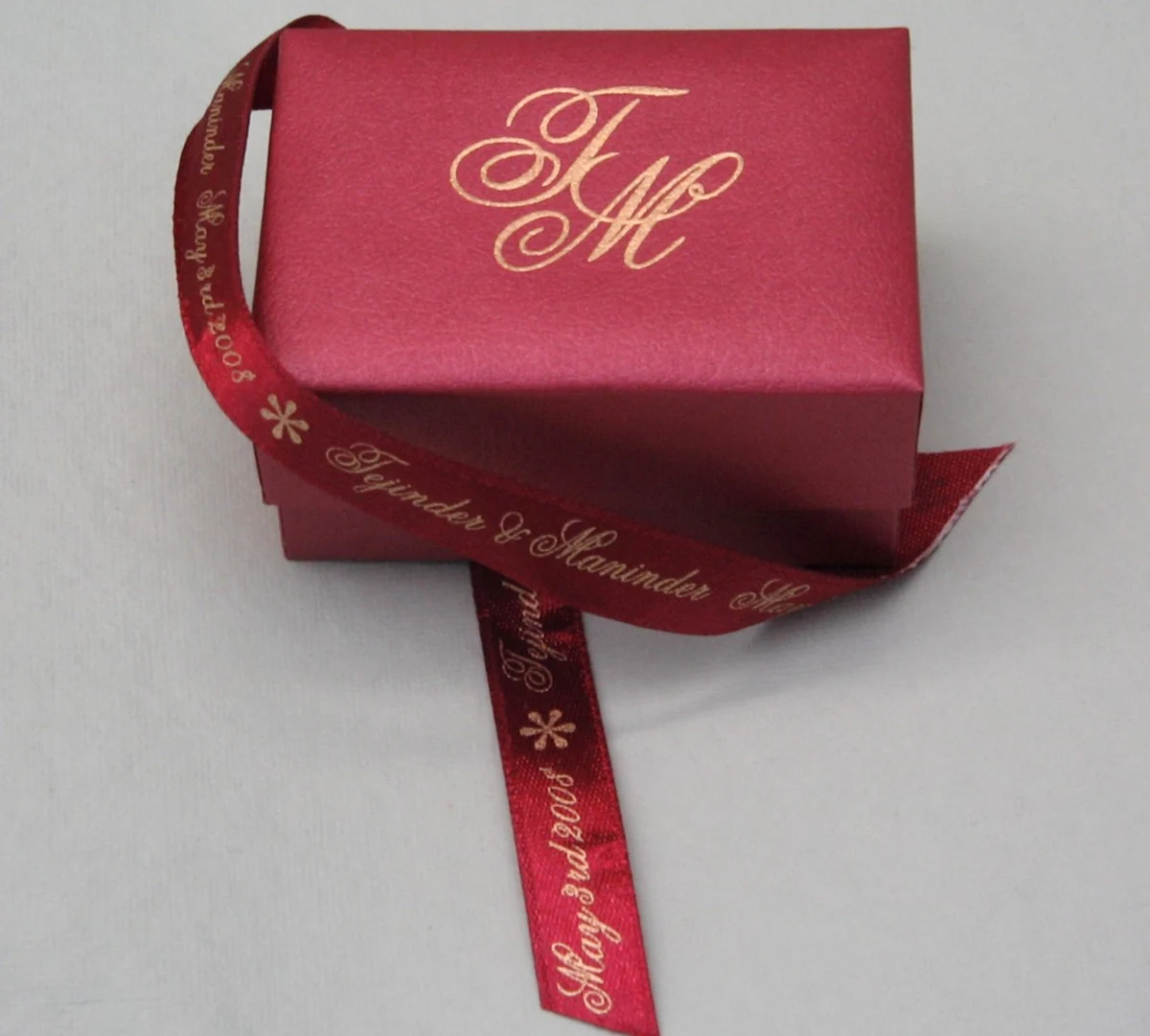 Burgundy gift box with a gold monogram and a matching printed ribbon
