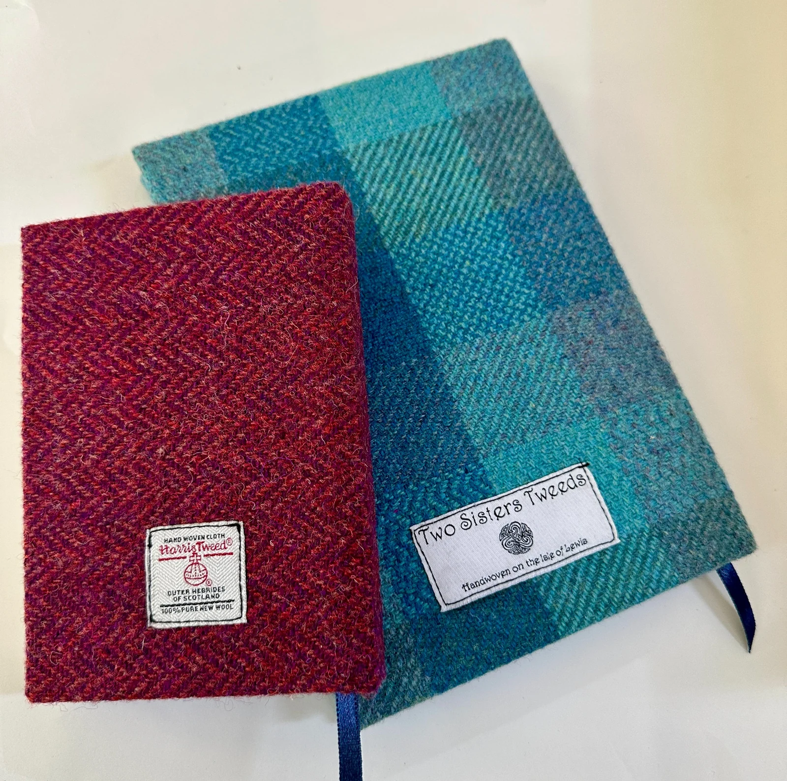 Red and blue woven fabric journals with stitched labels and ribbon markers